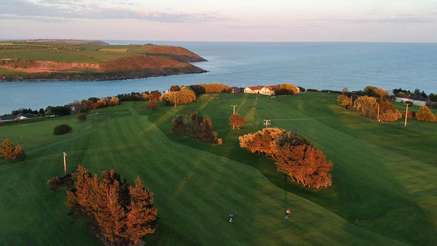 An aerial view of one the fairways at Youghal Golf Club with Youghal Bay in background set against an evening sky