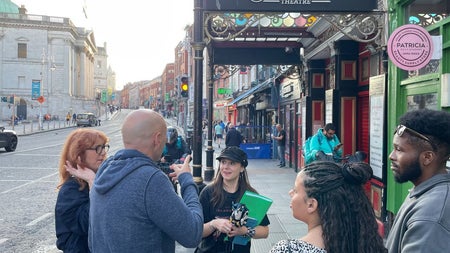 A walking group outside the Olympia Theatre as a guide shares stories with them