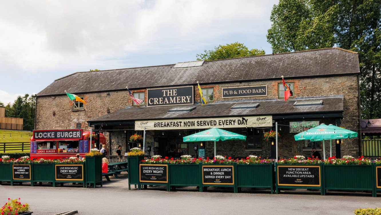 Exterior of an old stone building with outside dining area with green branded parasols