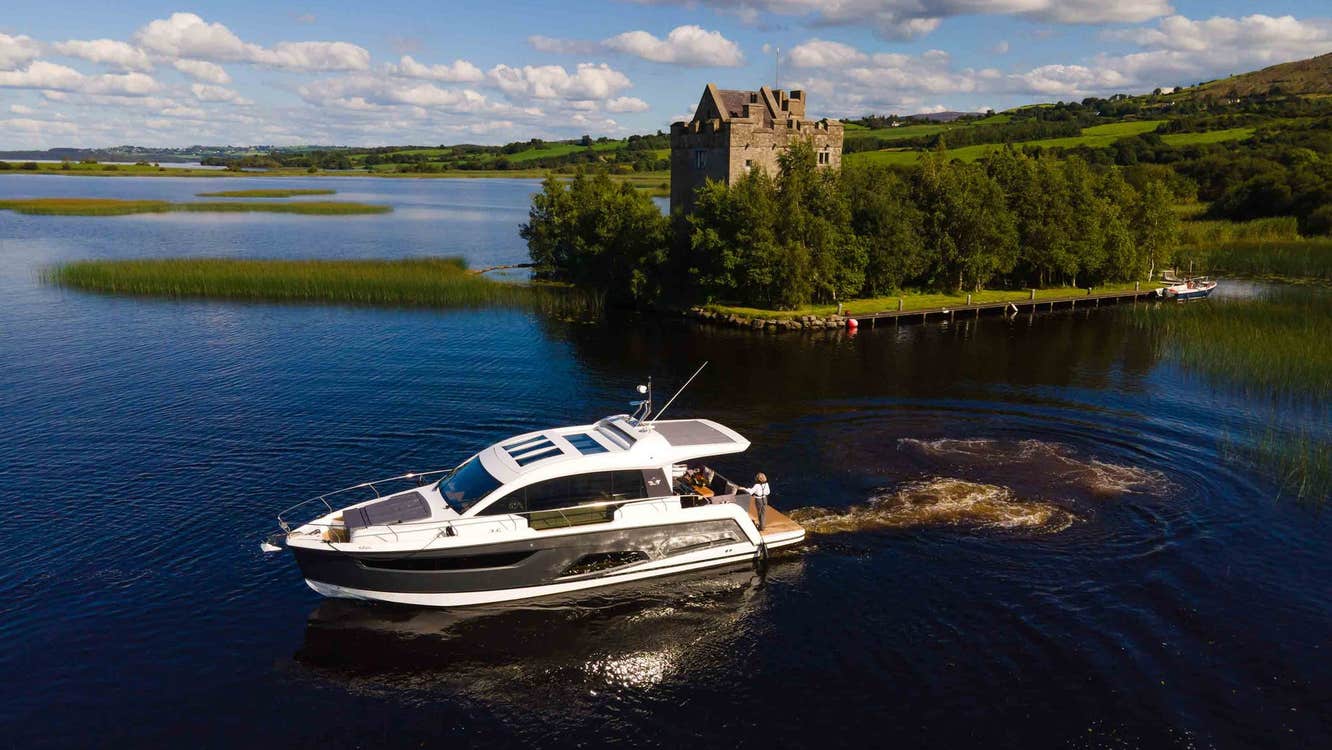 A boat on a large lake beside a small island with a castle surrounded by trees