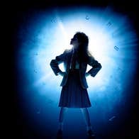 A silhouette figure of a child with their hands on their hips lit from behind with bright light.