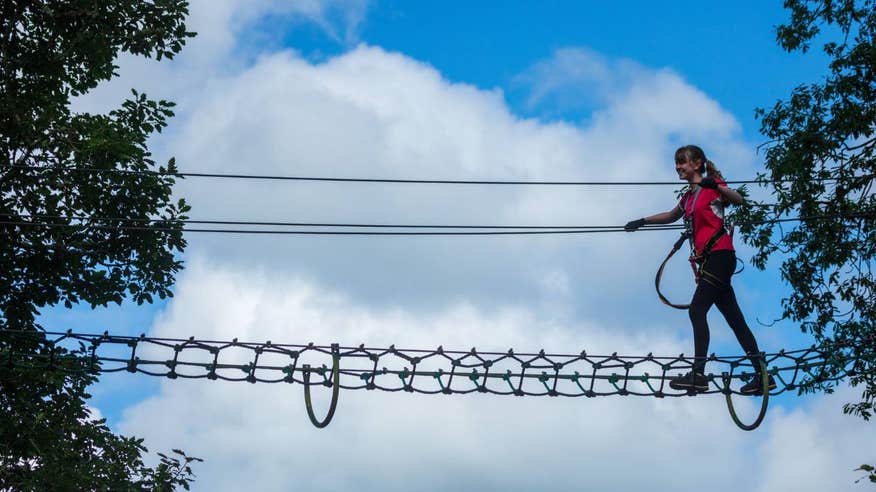 Young girl walking across a high ropes course in Carlingford Adventure Centre, Louth.