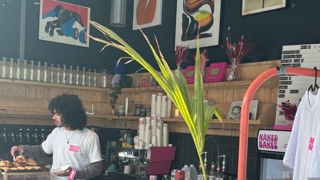Coffee shop with paintings on the wall and a person serving pastries