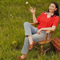 A woman seated in a wooden chair on grass