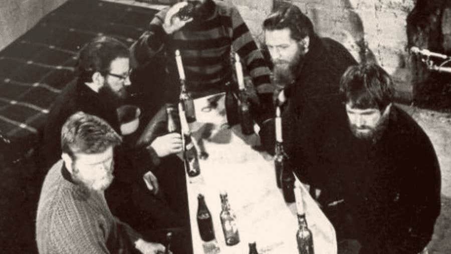 Old black and white photo of group of men seated at pub table