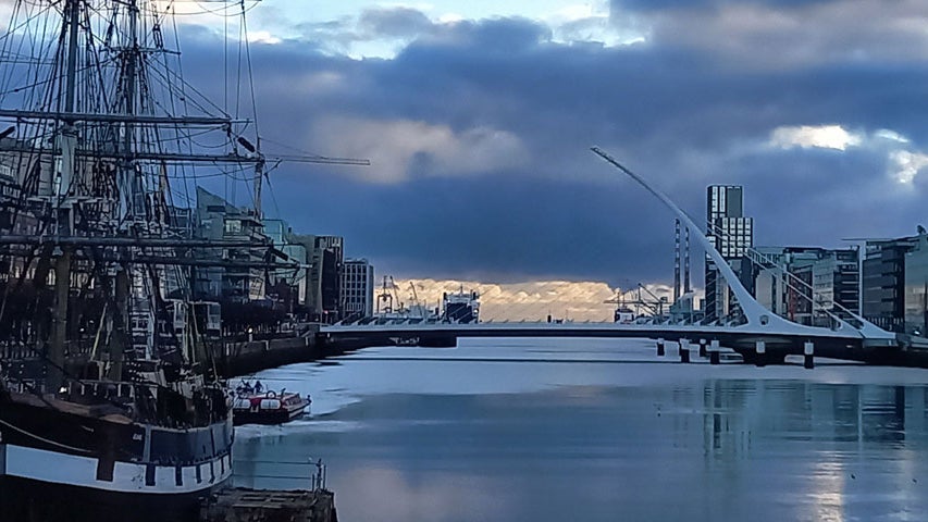 View of an old sailing ship with a bridge in background at sunset