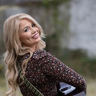 A smiling woman playing a guitar looking back over her right shoulder