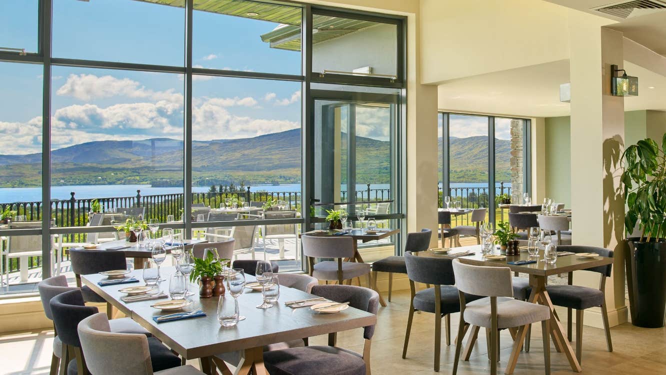 Interior of a brightly coloured restaurant with set tables and large panoramic windows with a view