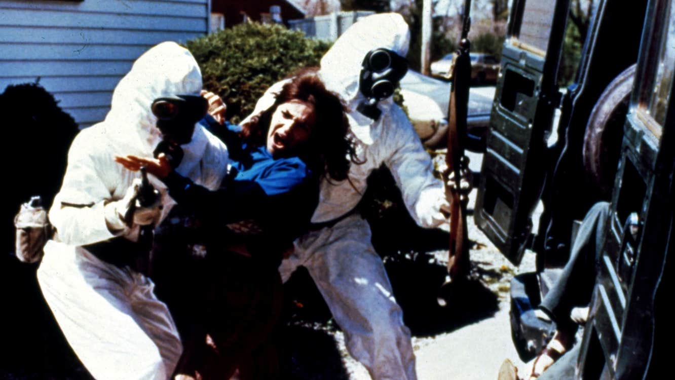 Armed men in hazmat suits are forcing a woman into a vehicle.