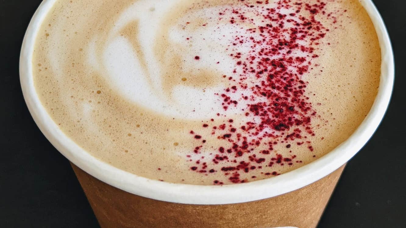 Filled take away coffee cup with pink sprinkles on the foam