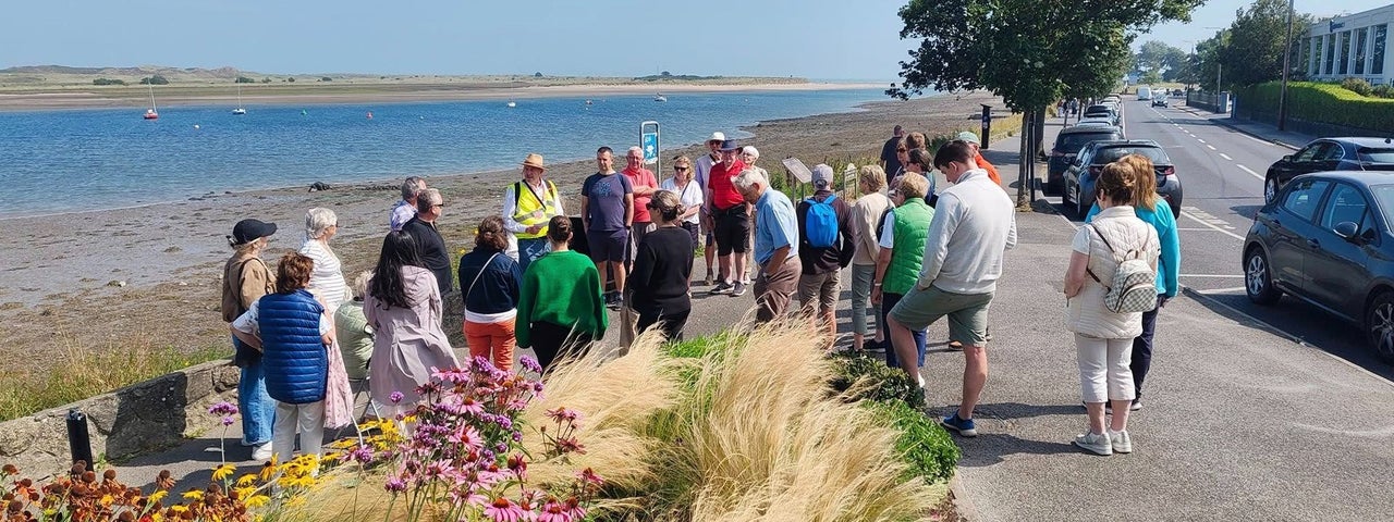 A group of people standing with their walking tour guide on the waterfront in Malahide