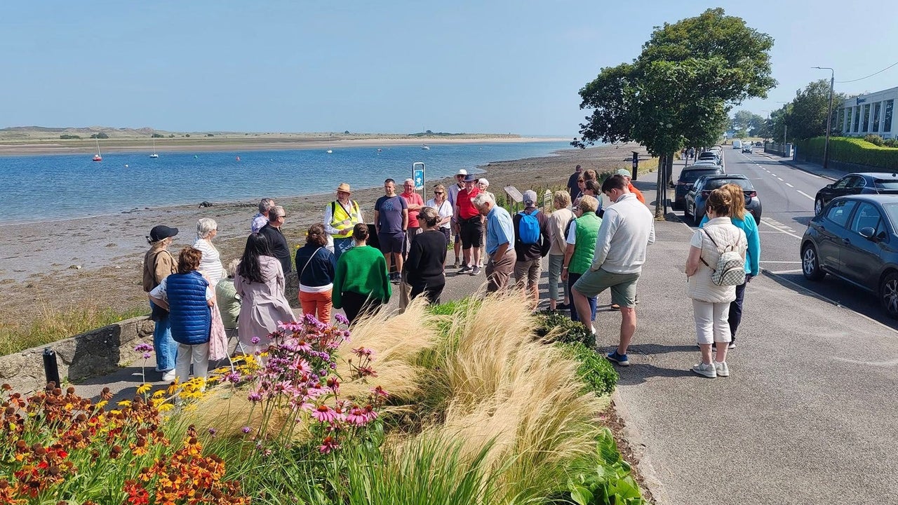 A group of people standing with their walking tour guide on the waterfront in Malahide