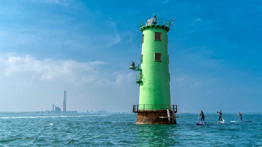 People stand-up paddleboarding beside North Bull Lighthouse on Dublin Bay