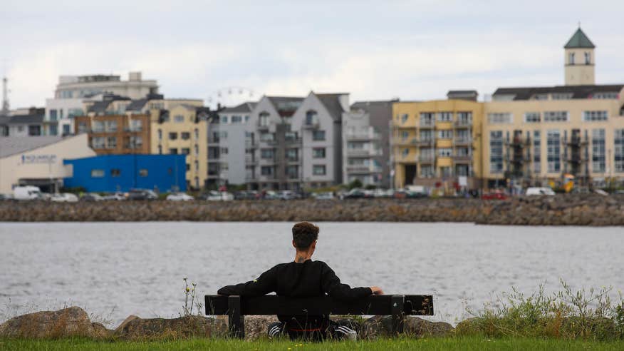 A man sitting on a bench along the Salthill Promenade in Galway city.