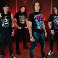 Group of 4 men in black T-shirts and long hair looking serious.