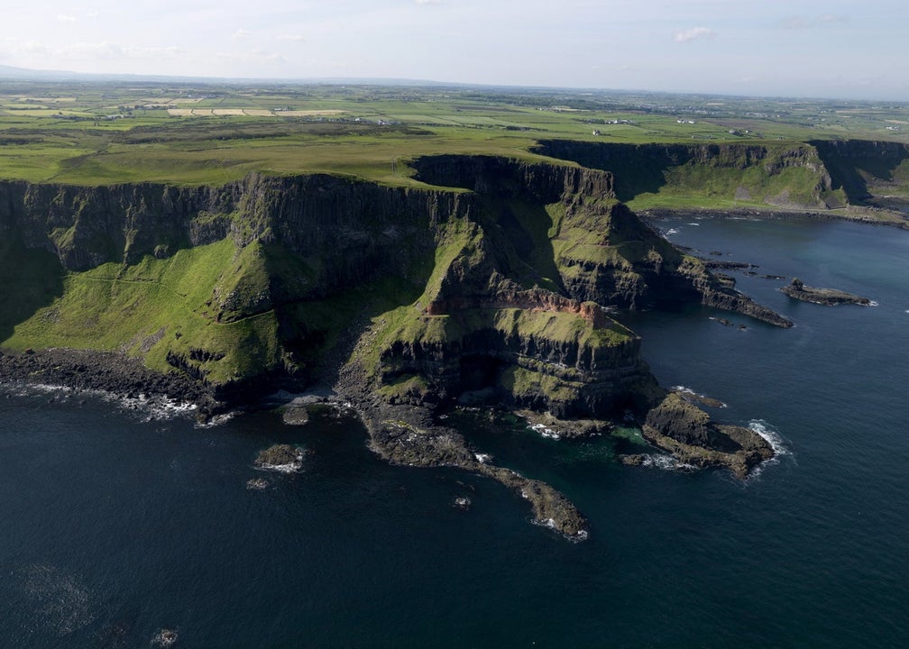 View of cliffs with flat green fields in the distance