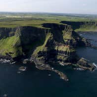 View of cliffs with flat green fields in the distance