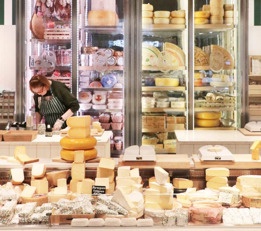 An extensive display of different cheeses in a retail shop setting