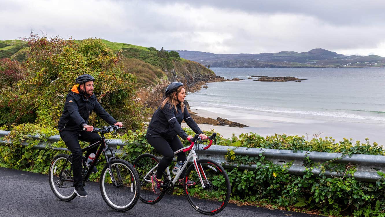 Couple cycling looking out on Marble Hill Beach in Donegal.
