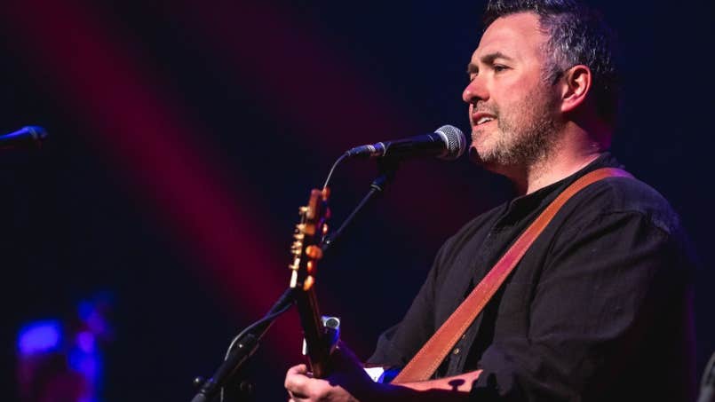Ger O'Donnell - Guest Singer - a man in dark top playing a guitar and singing into a mic on stand.