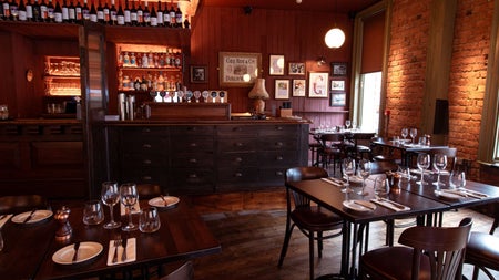 The dining area of a traditional pub with dark wood colours and tables set for dinner