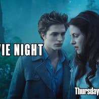 A man and woman standing near each other looking dramatic in a forest at twilight.