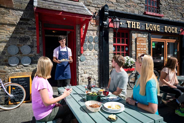 A waiter serving food to a table of people at The Long Dock restaurant in County Clare