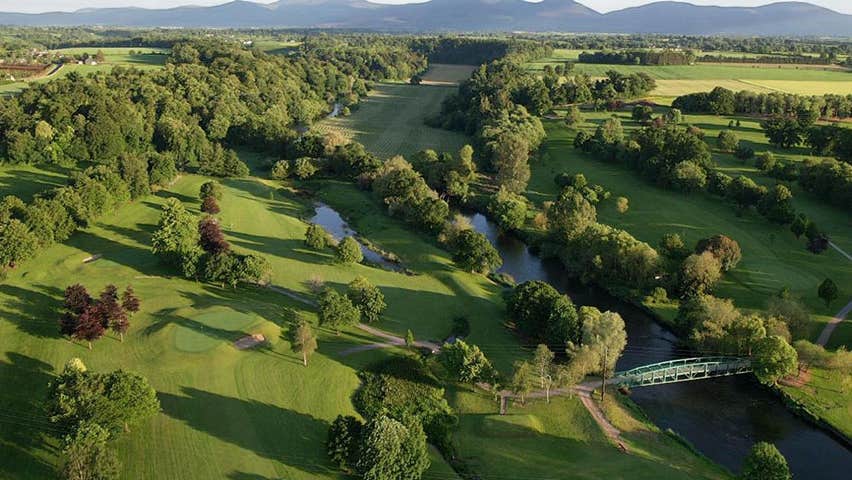 Aerial view of Cahir Park Golf Club green with lots of trees and mountains in the distance