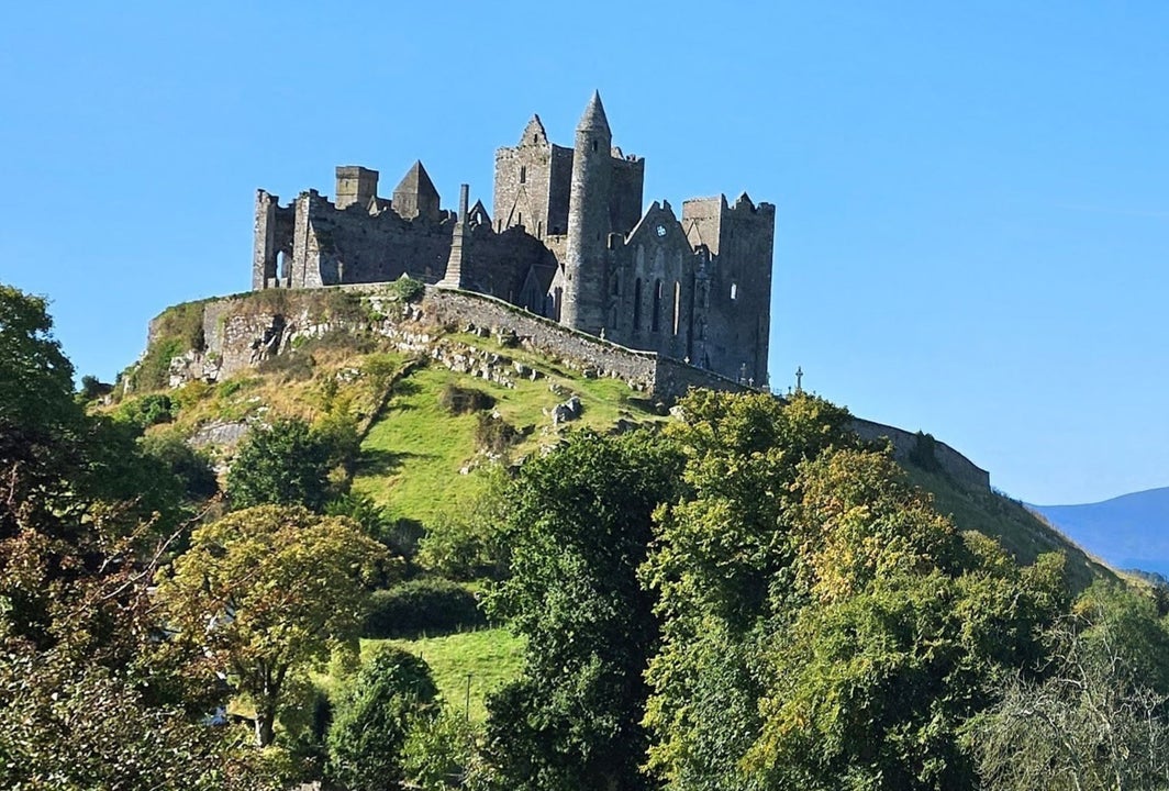 Group of early Christian buildings on top of a rocky hill against a blue sky backdrop