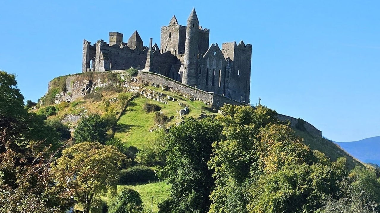 Group of early Christian buildings on top of a rocky hill against a blue sky backdrop