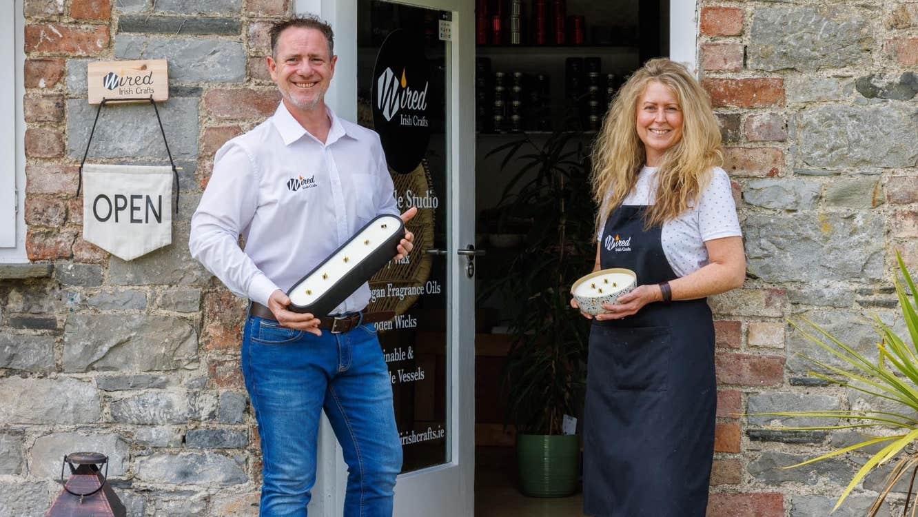 A lady and gentleman standing outside Wired Irish Craft holding candles