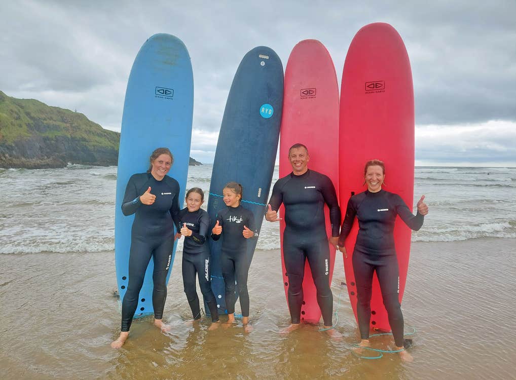 Murfs Surf School family standing in front of surfboards on the beach