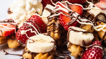 Churros with whipped cream chopped strawberries bananas and melted chocolate at Sweet Churro