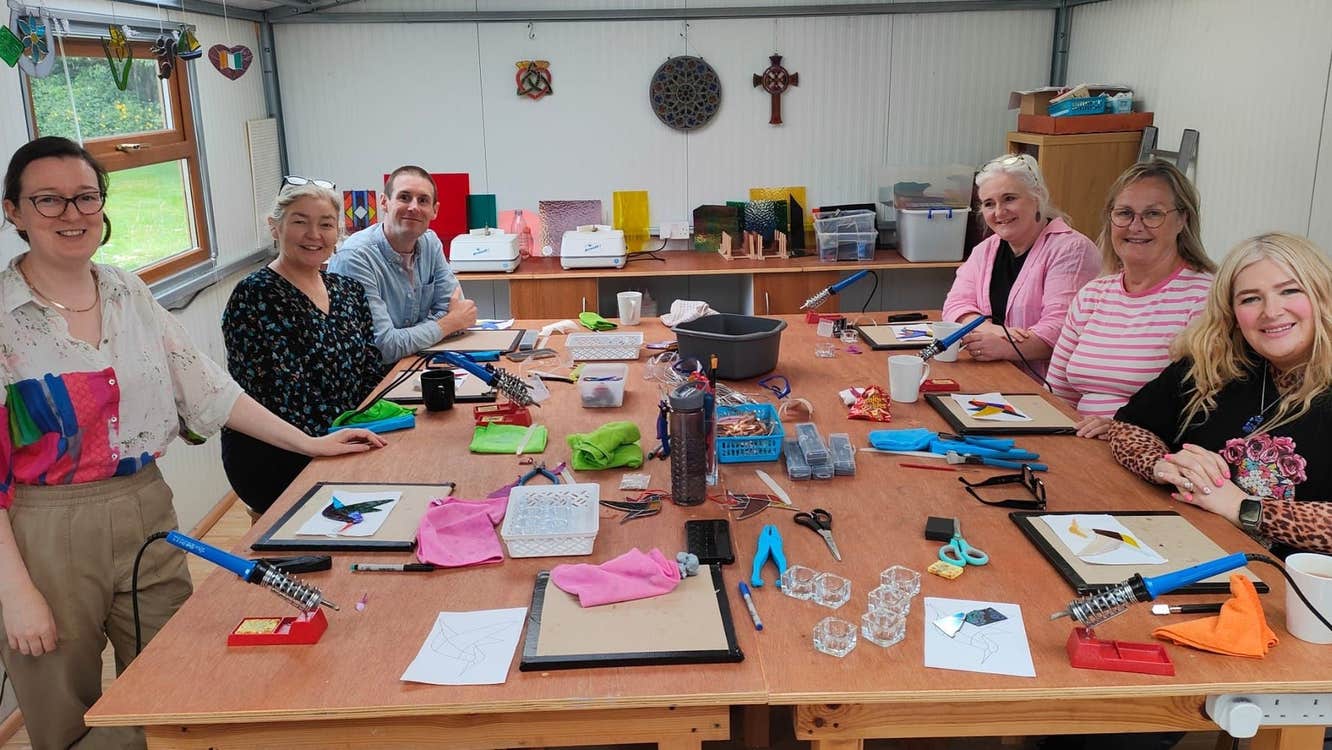 A group at a large workshop table with tools and materials in front of them