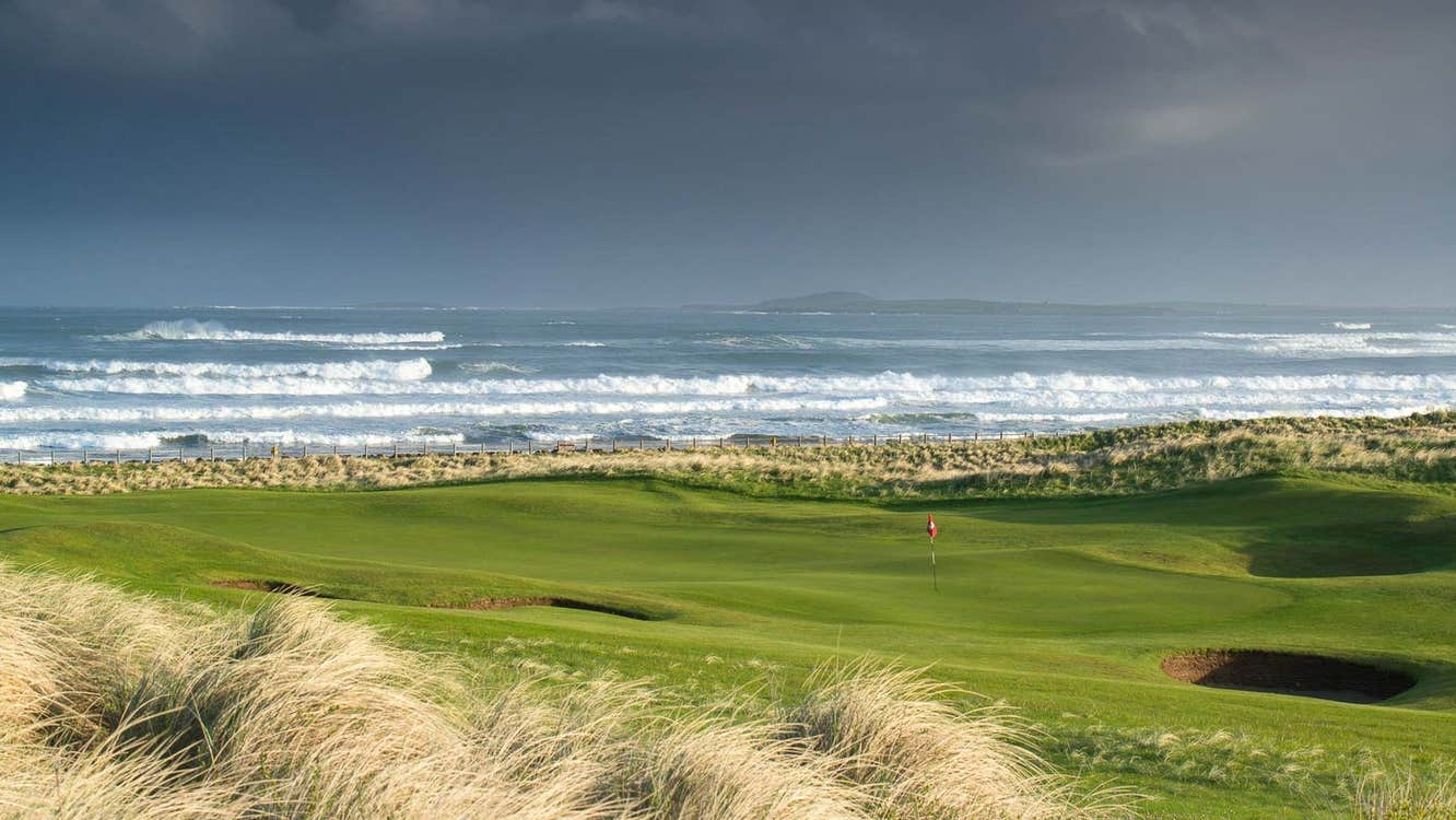 A golf course with a view of the sea as waves roll in