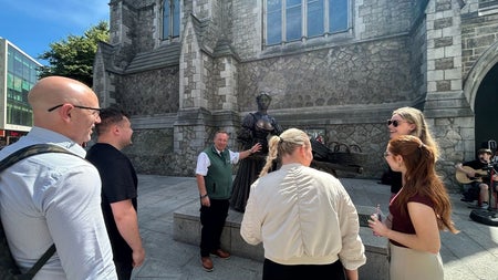 A tour group standing outside a historic building as a tour guide speaks