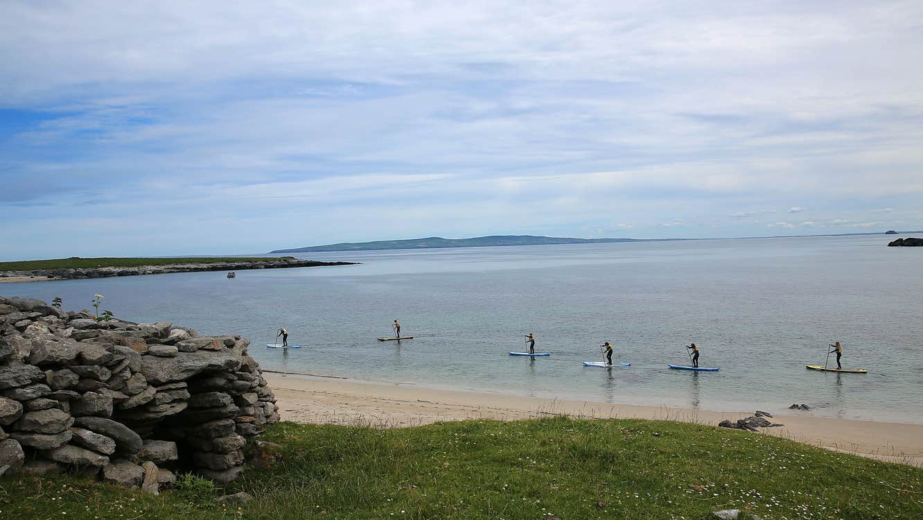 People enjoying a stand up paddle boarding lesson on Maharees Beach