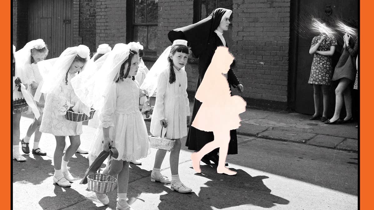 Black and white photo of girls in short white communion dresses and veils holding small baskets, being led along a street by a young nun.