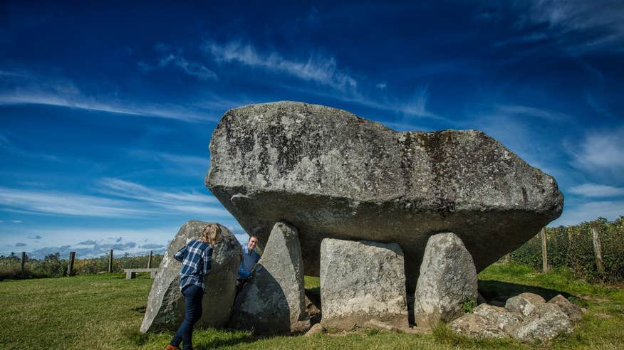 Two people exploring Brownshill Dolmen In County Carlow