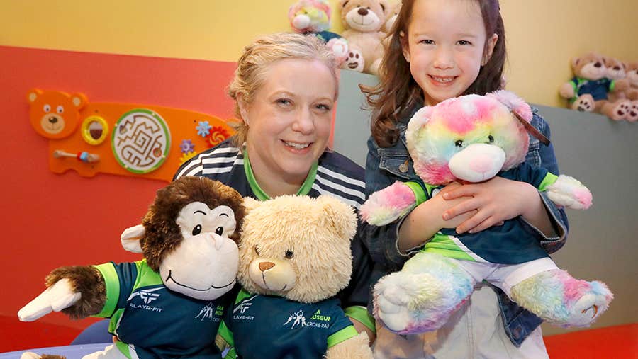 A smiling woman and child holding cuddly toys.