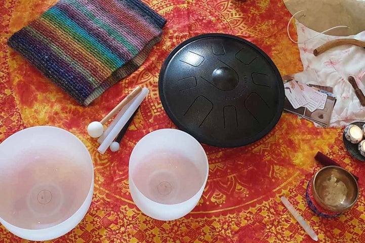 White, opaque glass bowls on a red and gold table cloth with small gongs and a stripy knitted piece of cloth.