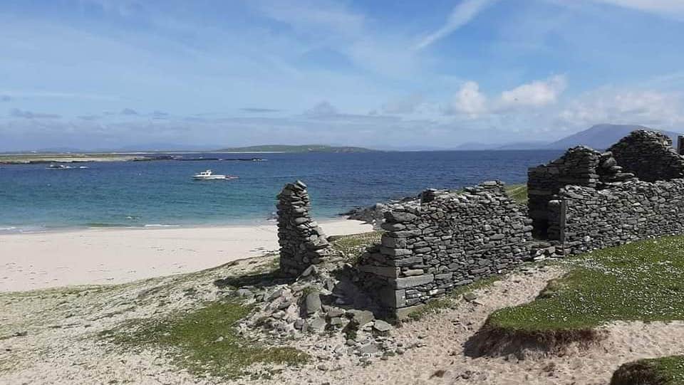 The ruins of a small stone cottage on a beach looking out to sea