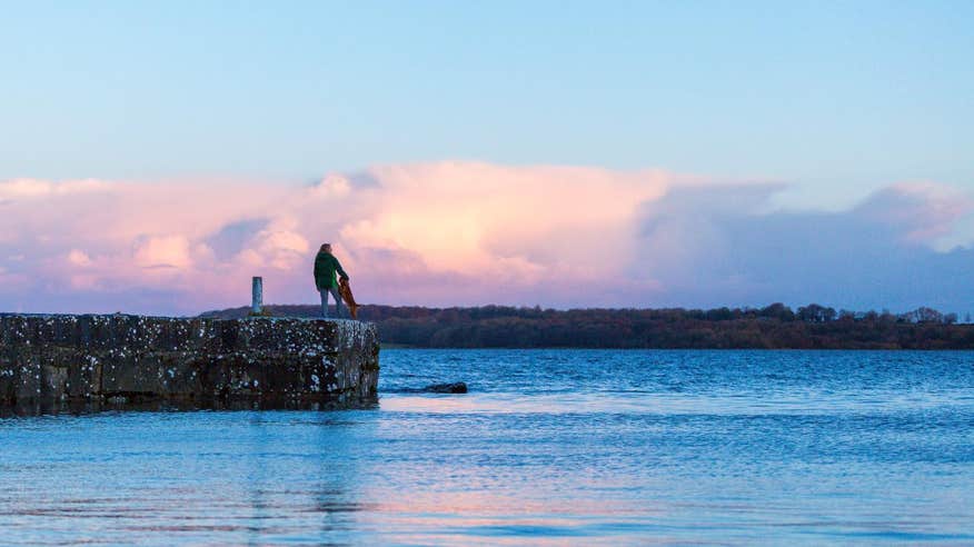 Woman and a dog watching the sunset at Lough Ree in Longford