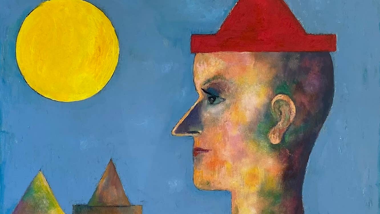 A contemplative clown stands in profile, dressed in a red hat and matching gown.