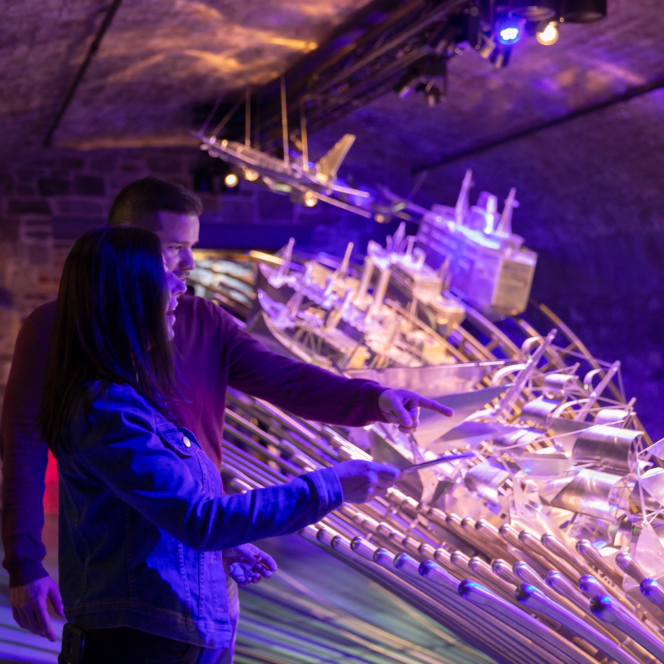 2 people pointing at an exhibit of ships.