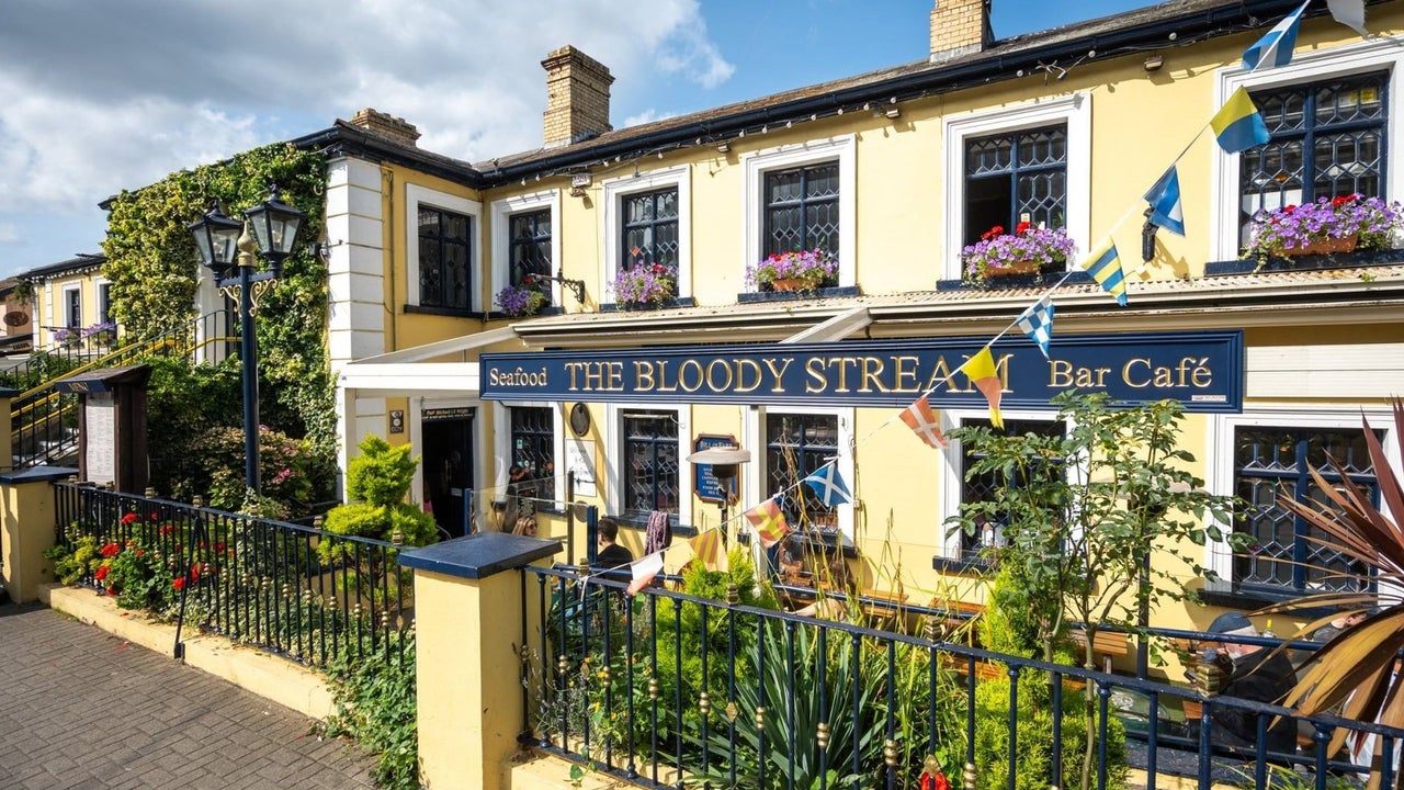 Exterior of a yellow pub with plants and blue railings in front