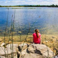 Girl sitting on the edge of a lake
