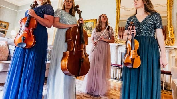 Glas Quartet, 4 women in long evening dresses holding musical instruments in an ornate room.
