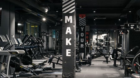 A spacious industrial style gym floor fitted with strength and cardio equipment