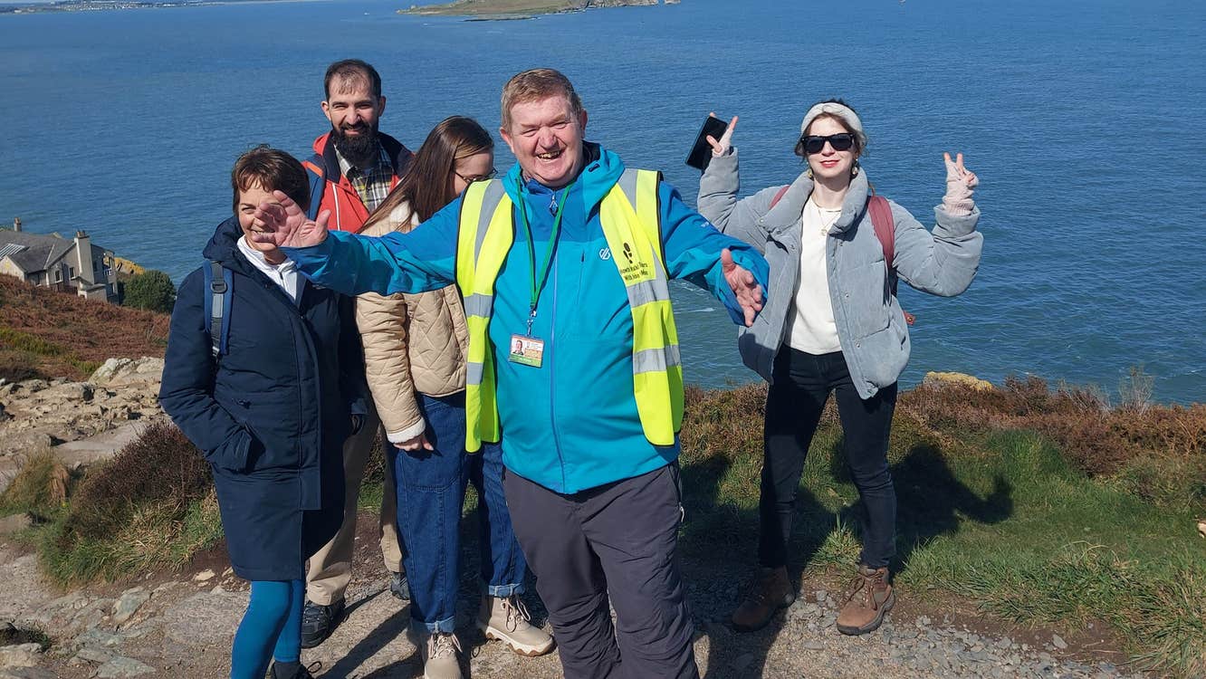 A group of people and a guide posing along a cliff top